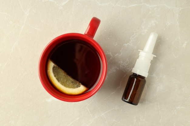 Bottiglia vuota di spray nasale e tazza di tè su sfondo chiaro