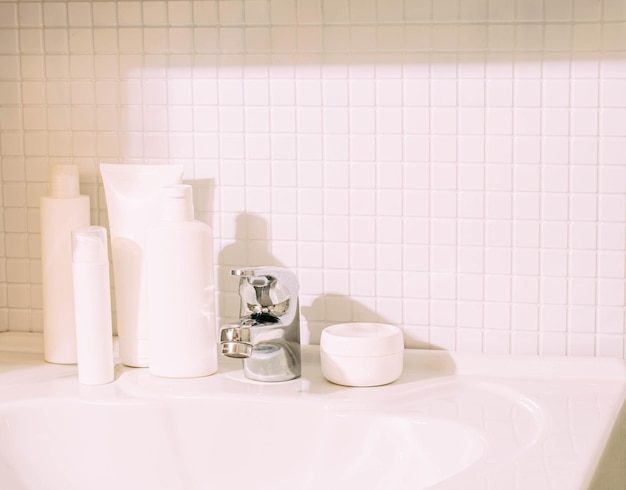 Bottiglie bianche con vari cosmetici si trovano sul lavandino in bagno Pulizia e ordine in casa