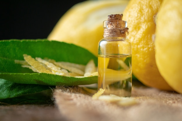 Bottiglie con olio essenziale di buccia di limone e foglia sul tavolo di legno