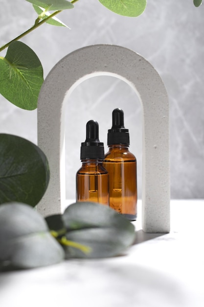 Bottiglie cosmetiche siero o olio in arco su sfondo di marmo grigio Cosmetici naturali concetto prodotto per la cura della pelle Concetto di bellezza per la cura del corpo del viso
