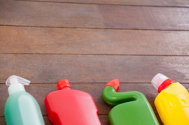 Bottiglie detergenti disposte su uno sfondo di pavimento in legno