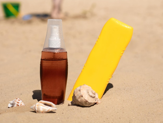 Bottiglie di abbronzante sulla sabbia sotto il caldo sole estivo conchiglie