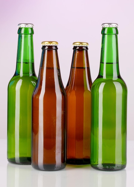 Bottiglie di birra in vetro colorato su sfondo viola