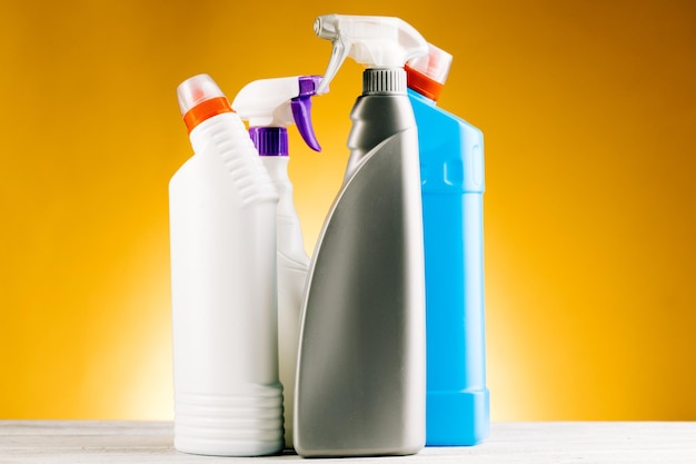Bottiglie di detersivo e prodotti per la pulizia su sfondo giallo.