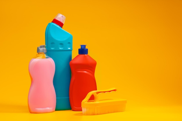 Bottiglie di detersivo per la pulizia della casa su sfondo giallo