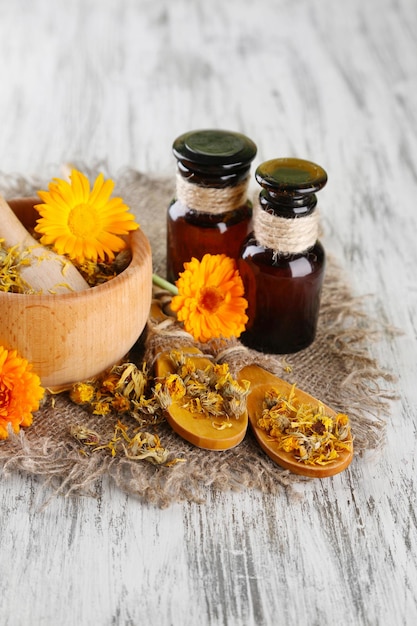 Bottiglie di medicinali e fiori di calendula su fondo di legno