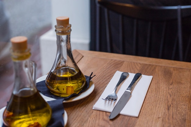 Bottiglie di olio e posate sul tavolo di legno in un caffè