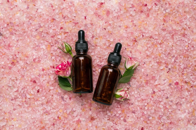Bottiglie di olio naturale con fiori e sale da bagno su sale da bagno rosa