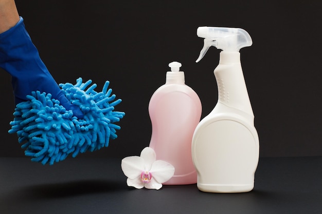 Bottiglie di plastica di fiori di orchidea liquido di lavaggio e una mano in un guanto di gomma che tiene uno straccio