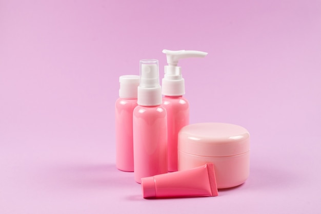 Bottiglie di plastica rosa per prodotti per l'igiene, cosmetici, prodotti per l'igiene su uno sfondo rosa.