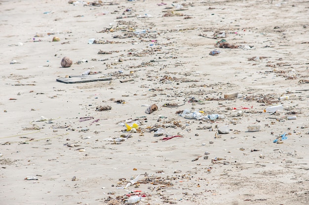 Bottiglie di rifiuti, vetro e borsa di plastica sulla spiaggia.