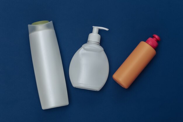 Bottiglie di shampoo su sfondo blu classico. Colore 2020. Vista dall'alto