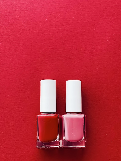 Bottiglie di smalto rosso e rosa su sfondo rosso concetto di manicure e cosmetici di bellezza