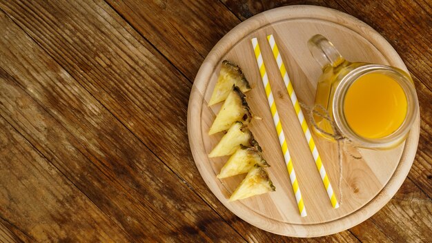 Bottiglie di succo d'ananas su un tavolo di legno. Bevanda gialla e ananas fresco. Spuntino al resort. Foto d'estate. Vista dall'alto