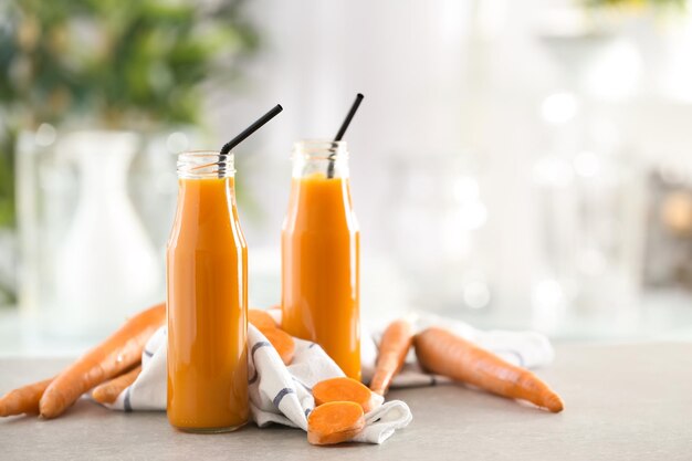 Bottiglie di succo di carota fresco su sfondo sfocato