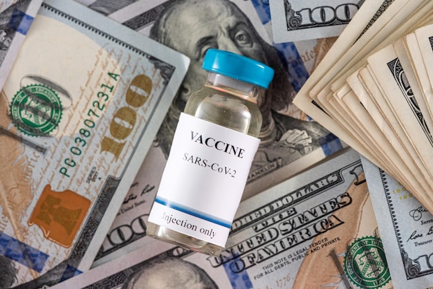 Bottiglie di vaccino durante una pandemia con una calcolatrice con una grossa somma di banconote da un dollaro
