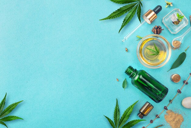 Bottiglie di vetro con olio di CBD, foglie di canapa tintura THC su sfondo blu. Cosmetics CBD olio di canapa.