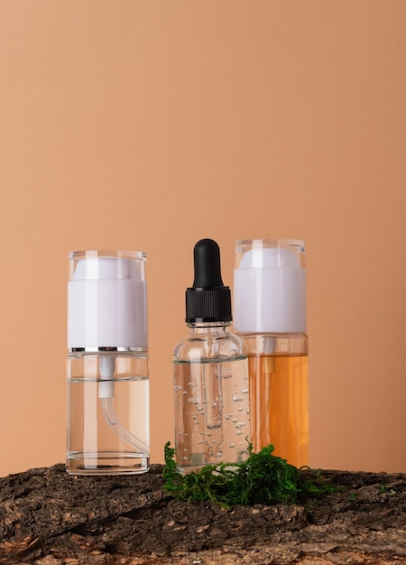 Bottiglie di vetro con prodotti per la cura della pelle, corteccia di muschio e un ramo decorativo di legno