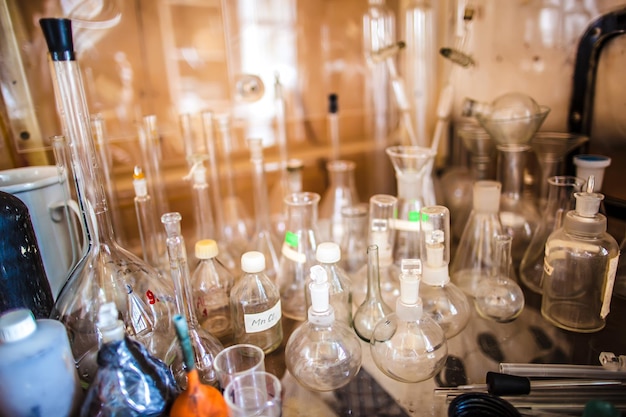 Bottiglie di vetro, provette, boccette e tazze sono sul tavolo in un vecchio laboratorio chimico