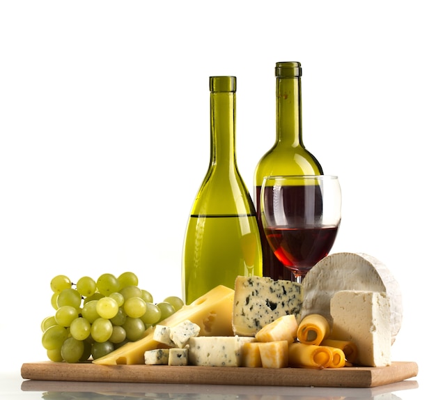 Bottiglie di vino, bicchiere di vino, formaggi e uva sul piatto di legno