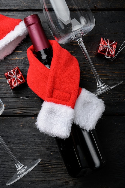 Bottiglie di vino Buon Natale e Felice Anno Nuovo insieme, su sfondo di tavolo in legno nero, vista dall'alto piatta