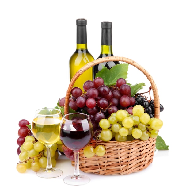 Bottiglie e bicchieri di vino e uva in cesto isolato su bianco
