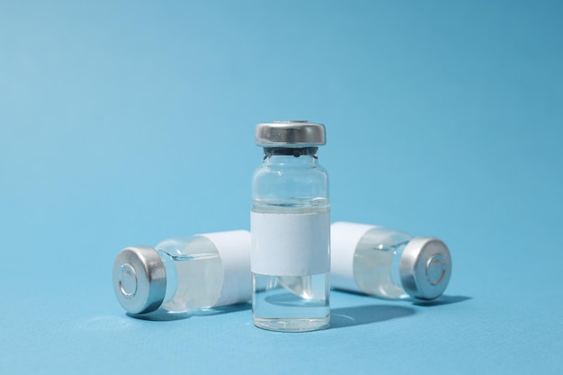 Bottiglie mediche di vetro con vaccino su sfondo blu da vicino