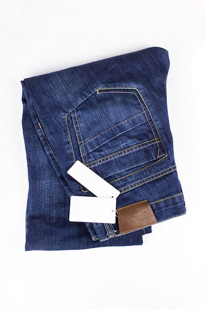 Bottone dei jeans di moda. Jeans blu che si trovano su fondo bianco con il cartellino del prezzo. Copia spazio. Abbigliamento, concetti di negozio online.