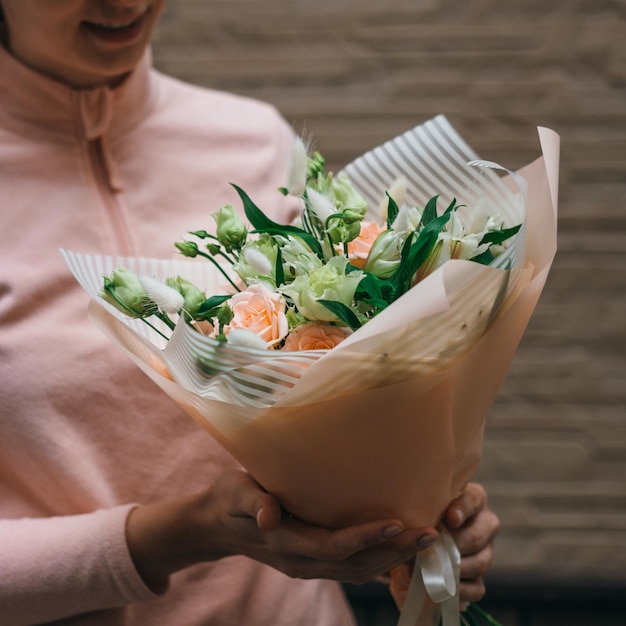 Bouquet colorato di diversi fiori freschi nelle mani di una donna fiorista Sfondo di fiori rustici