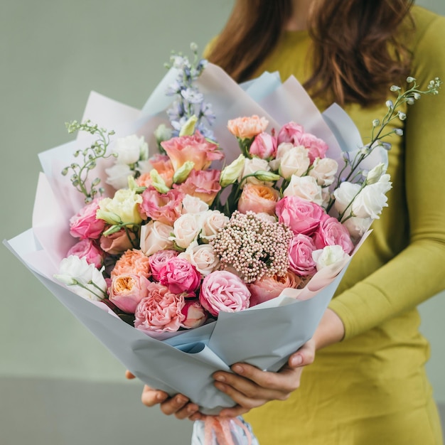 Bouquet colorato di diversi fiori freschi nelle mani di una donna fiorista Sfondo di fiori rustici