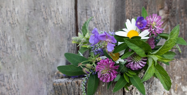Bouquet colorato di fiori di prato su uno sfondo di legno con un posto per il testo Cartolina