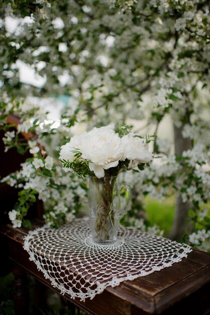 Bouquet con fiori di peonie bianche sul tavolo in giardino