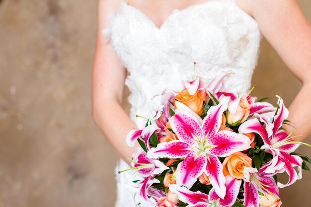 Bouquet da sposa con gigli rosa e rose arancioni.