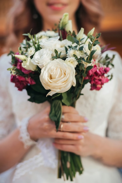 Bouquet da sposa con rose bianche nelle mani della sposa