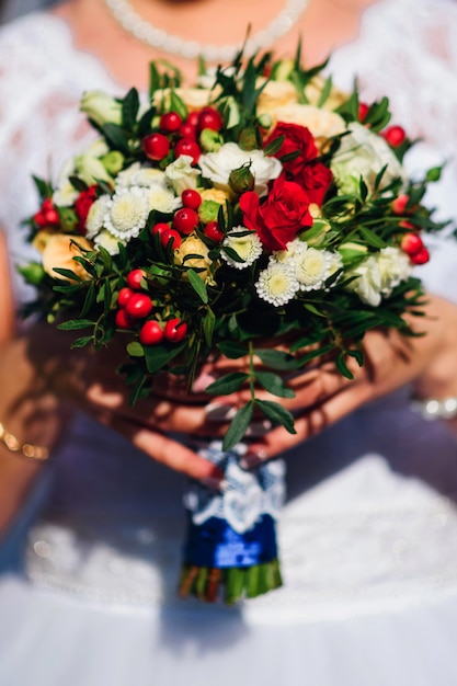 Bouquet da sposa con rose rosse e margherite bianche nelle mani della sposa