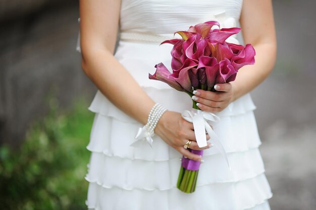 Bouquet da sposa di fiori viola nelle mani della sposa