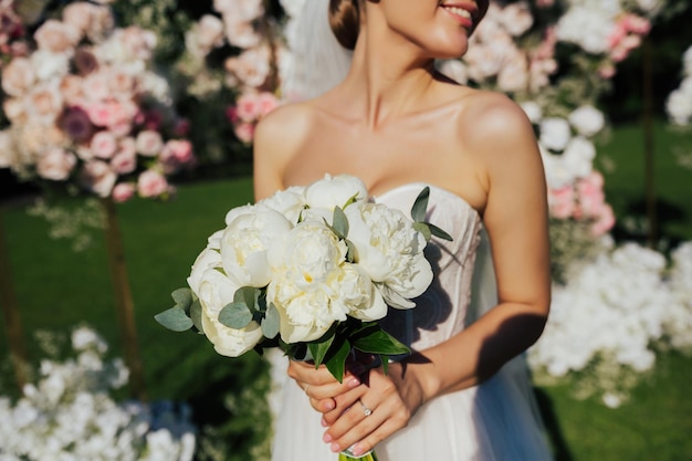 Bouquet da sposa di peonie bianche in mano alla sposa