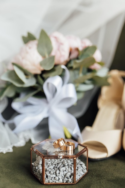 Bouquet da sposa di peonie bianche, scarpe e fedi nuziali su fondo di legno