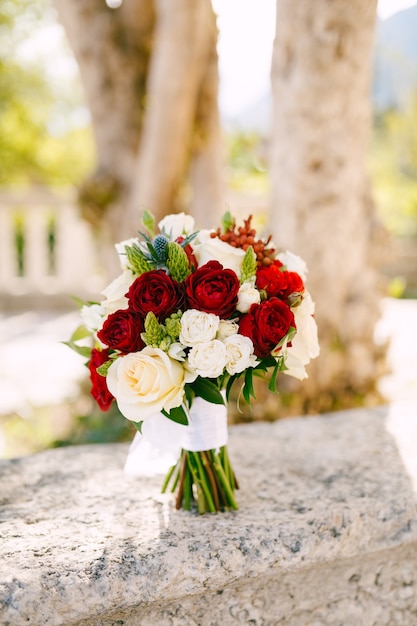 Bouquet da sposa di rose bianche leggere e crema ornithogalum eryngium con nastri bianchi sul recinto