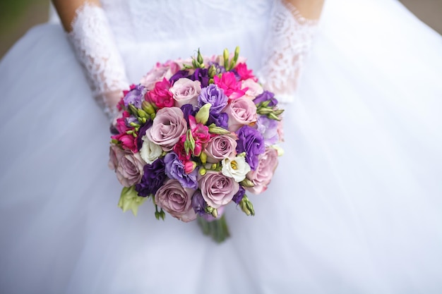 Bouquet da sposa di rose bianche rosse e rosa nelle mani della sposa