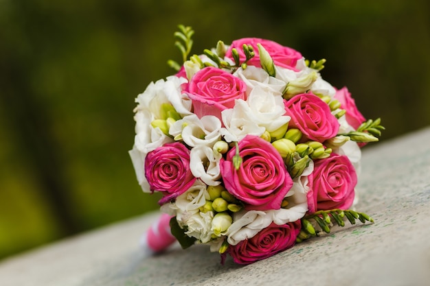 Bouquet da sposa di rose bianche rosse sdraiate su una pietra