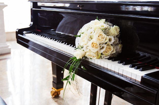 Bouquet da sposa di rose in appoggio sui tasti di un pianoforte nero