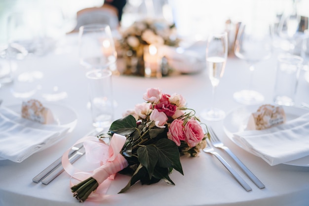 Bouquet da sposa di rose rosa eustoma hedera e nastri rosa sul tavolo del matrimonio