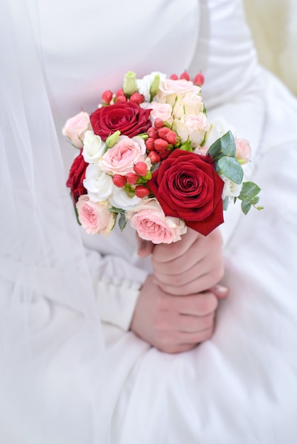 Bouquet da sposa di rose rosse e rosa nelle mani del primo piano della sposa