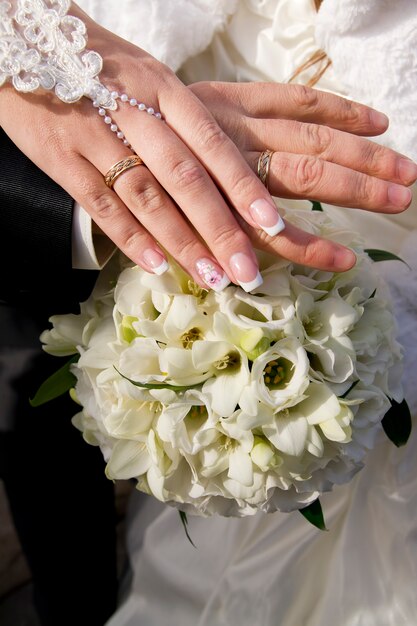 Bouquet da sposa e mani con anelli Fiori bianchi
