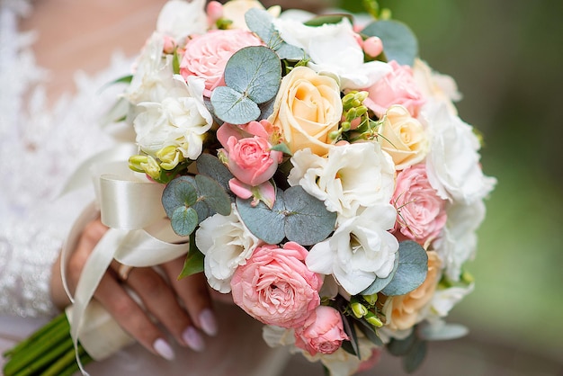 Bouquet da sposa grande nelle mani della sposa con decorazioni di rose bianche e rosa