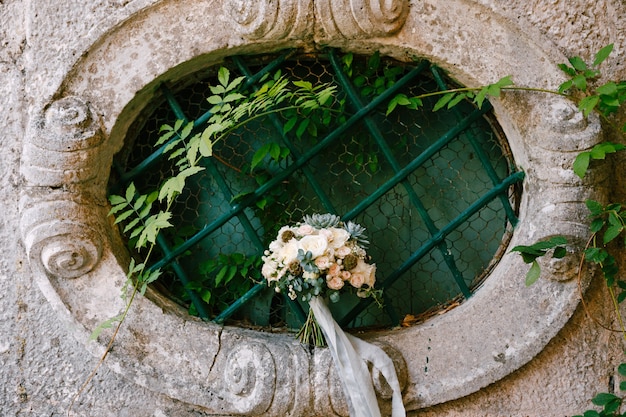 Bouquet da sposa su una finestra ovale di un'antica casa