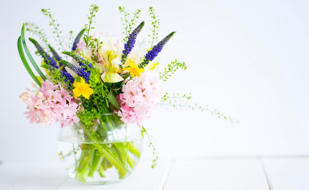 Bouquet delicato in un vaso di vetro su sfondo chiaro. Immagine con messa a fuoco selettiva