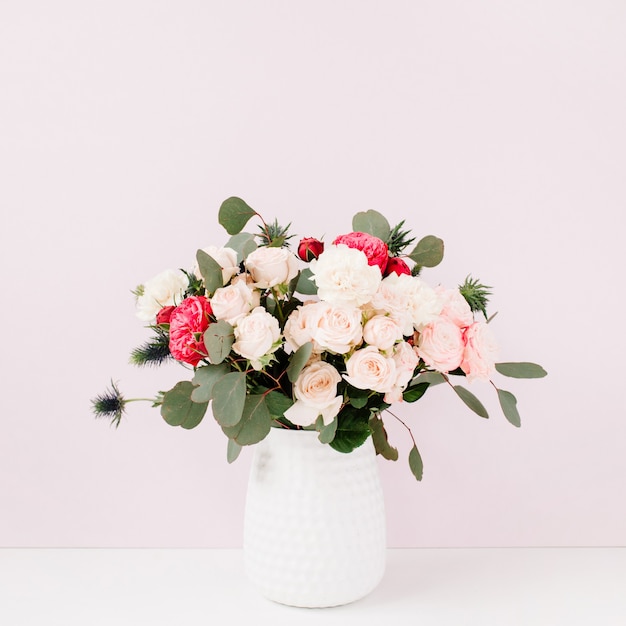 Bouquet di bellissimi fiori in vaso di fiori vicino alla parete rosa pastello pallido