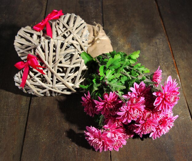 Bouquet di crisantemo rosa e cuori sulla tavola di legno